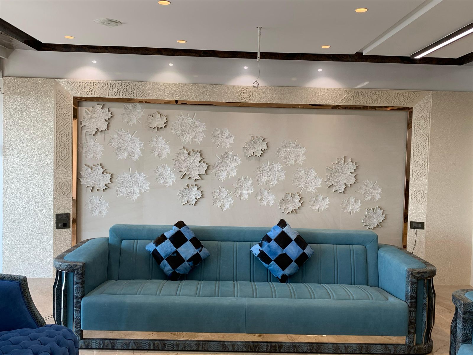 Luxury lounge sitting area featuring plush sofa set against a hand-carved maple leaf stone relief feature wall