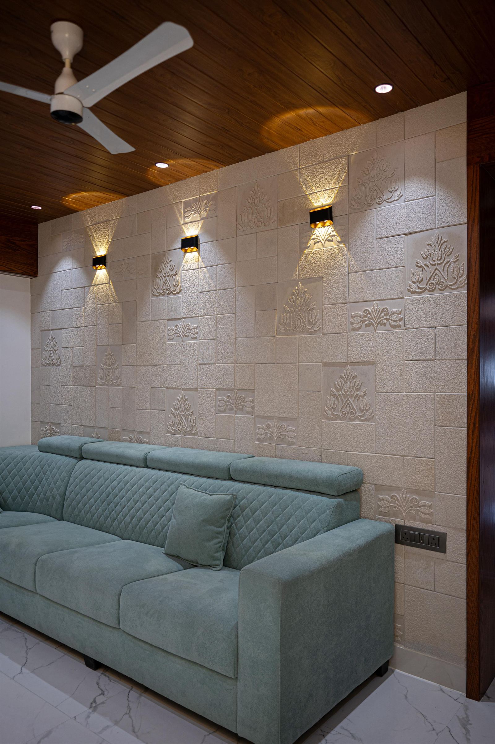 Contemporary sitting area with tufted sectional sofa against an illuminated textured carved stone relief wall