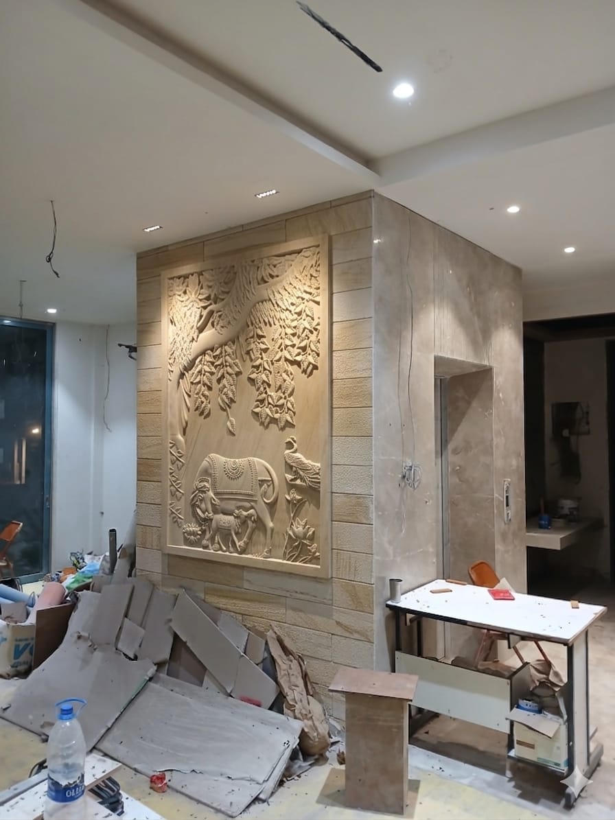 Grand entrance foyer wall featuring sculpted sandstone Kalpavriksha tree of life, royal elephant, and dancing peacock mural