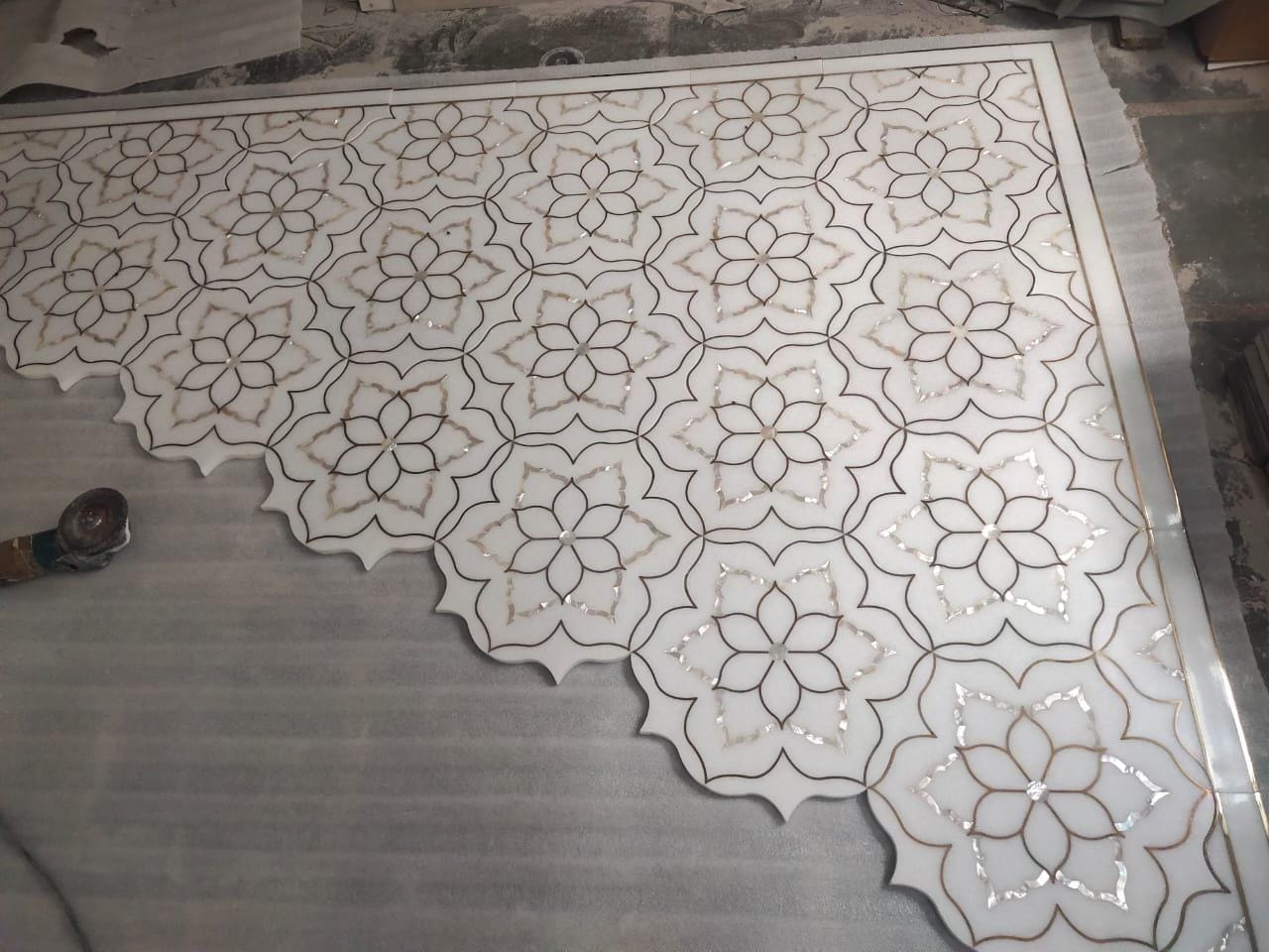 Master craftsman hand-assembling and dry-fitting intricate marble and mother-of-pearl inlay floor panels