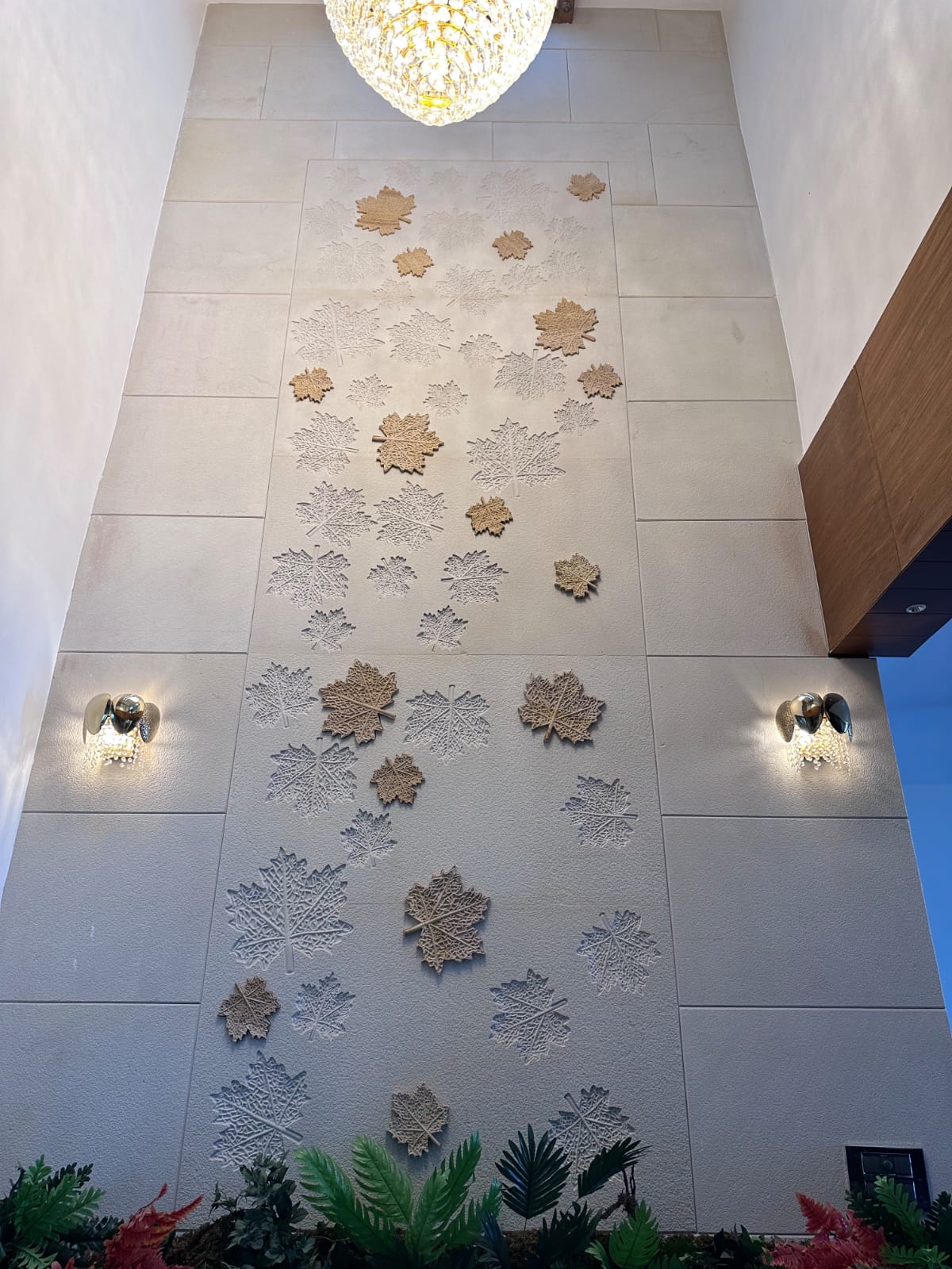 Double-height luxury living hall with crystal chandelier and carved sandstone botanical mural panels
